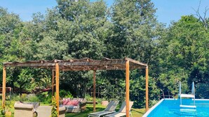 Un espace aménagé au bord de la piscine, comprenant une pergola, des chaises longues et une petite piscine.