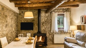 Une pièce chaleureuse avec un mur en pierre, une cheminée, une table dressée pour le repas et un canapé en cuir.