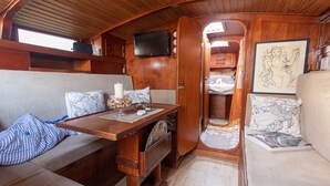 A compact, wood-paneled interior with a sofa, a small table, a television mounted on the wall, and a framed artwork.