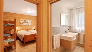 A wooden room with a bed, a nightstand, and a wall-mounted painting. - Holiday Apartment 'Casa Silvia' with Mountain View, Terrace & Wi-Fi (Livigno)