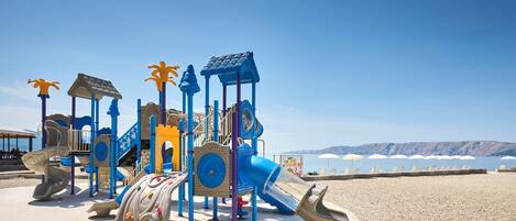 Un parque infantil en la playa con toboganes y estructuras para escalar.