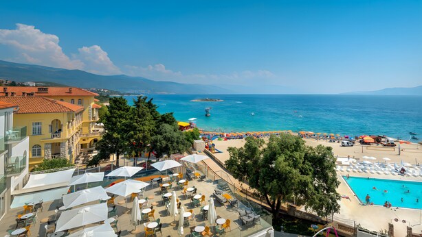 Un complejo turístico frente al mar con terraza, piscina y acceso a la playa.