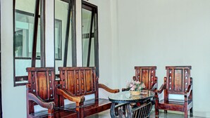 Una habitación con un banco de madera y una mesa redonda con cubierta de vidrio, junto a una cesta de flores.