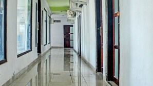 Un pasillo largo y estrecho con ventanas grandes a un lado y puertas al otro.