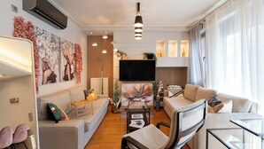 A modern living room with a sofa, armchairs, a coffee table, and a TV. - The Luxury Loft by Cloudkeys (Athens)