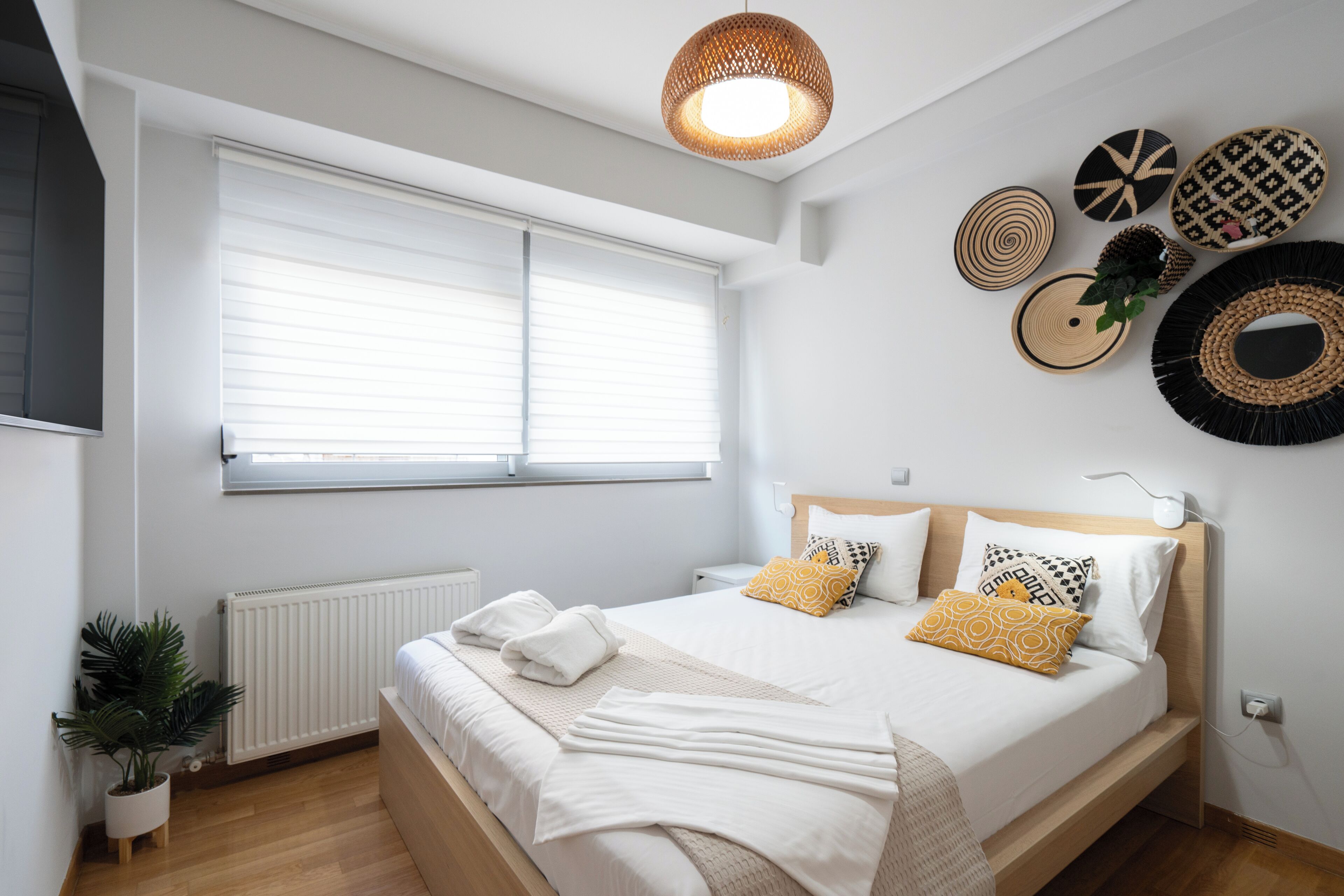 A modern bedroom with a large bed, a potted plant, and decorative wall art.