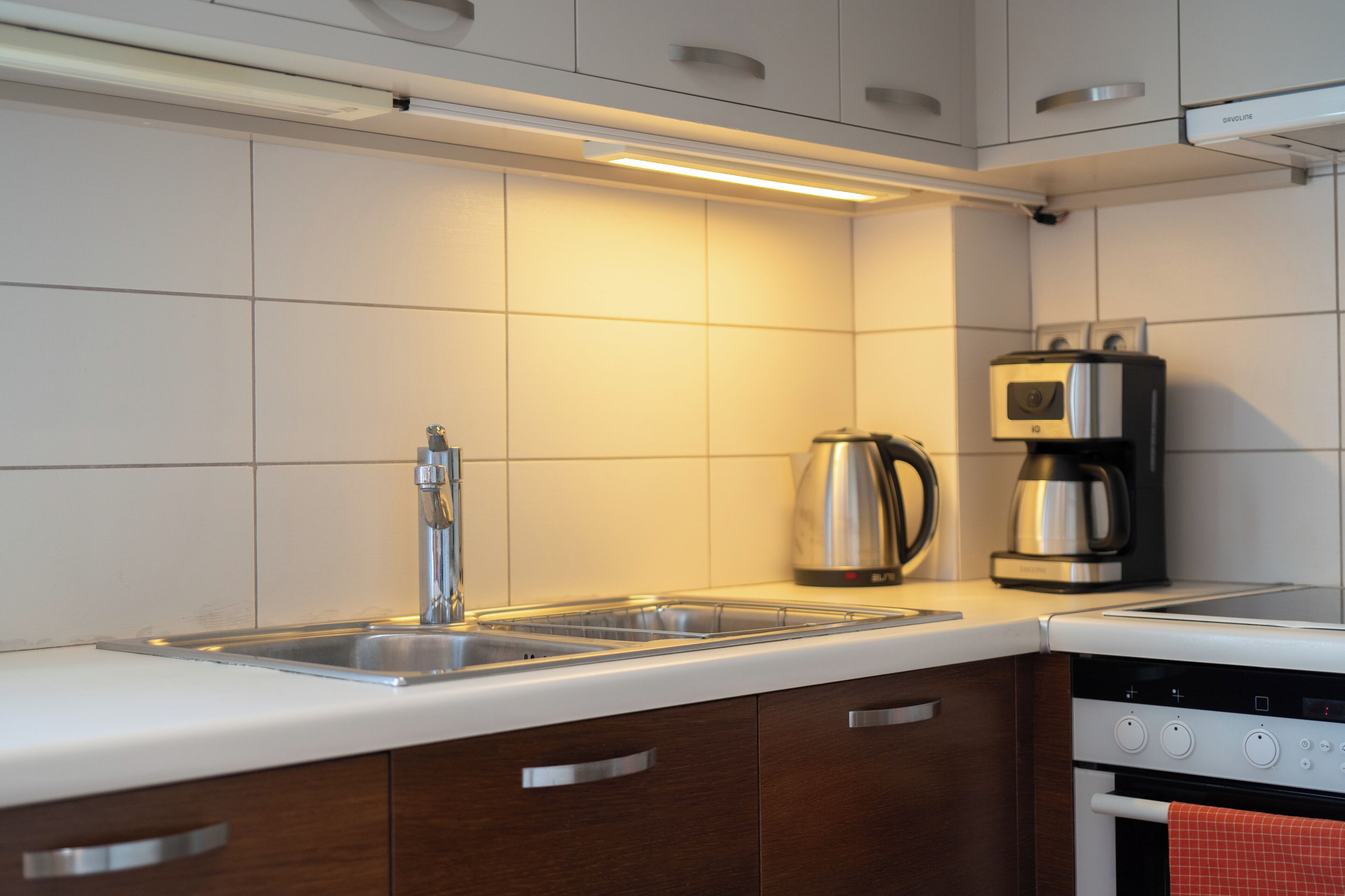 A modern kitchen with a stainless steel sink, a coffee maker, and a built-in oven.