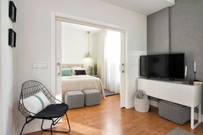 Una camera da letto moderna con un letto, un comodino, una TV e una sedia.