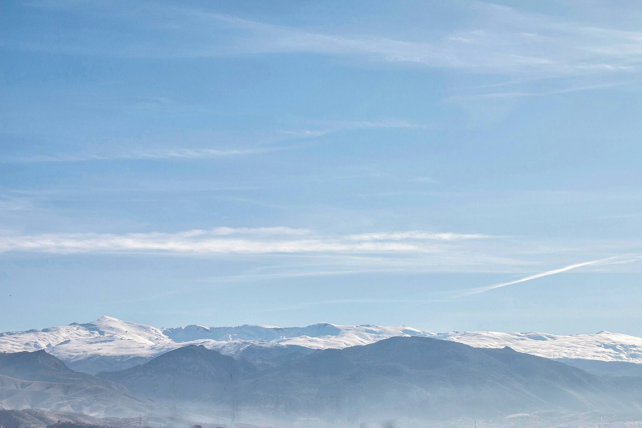 A mountain range with snow-covered peaks under a clear sky.