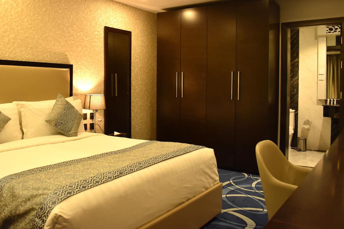 Ein Hotelzimmer mit einem großen Bett, einem Schreibtisch, einem Sessel und einem Kleiderschrank.