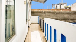 Un pasillo estrecho con suelo de baldosas que conduce a un balcón con detalles azules.