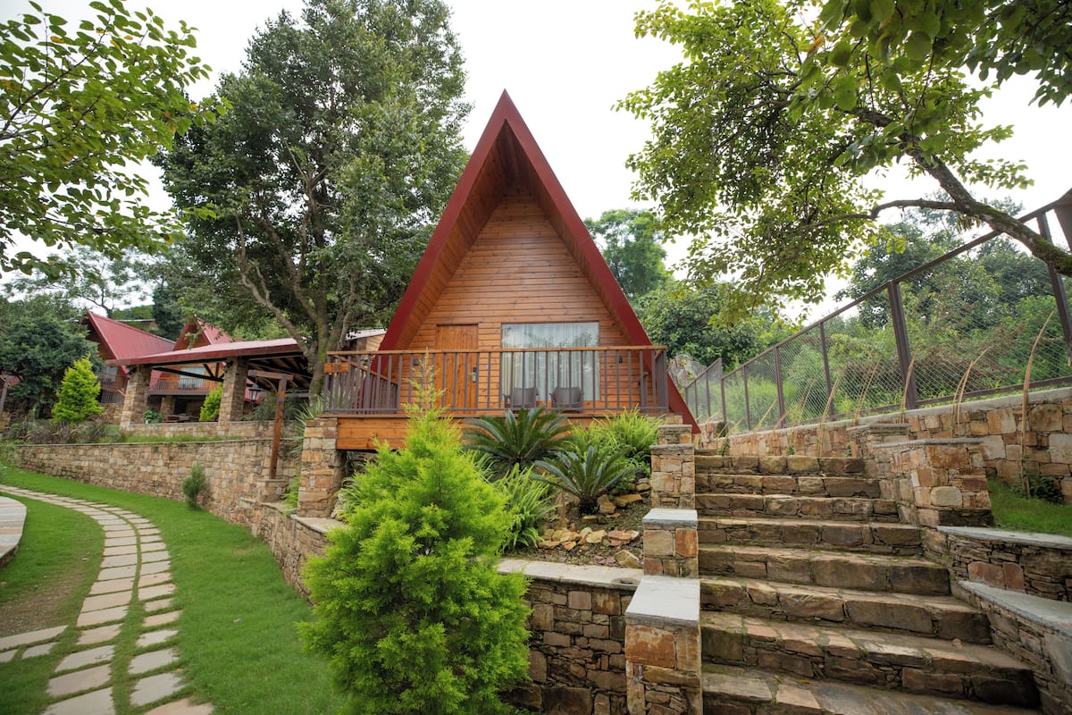 A wooden cabin with a stone staircase leading to a wooden deck.