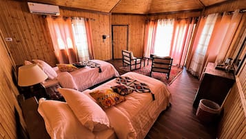 Un dormitorio de cabaña de madera con dos camas, un escritorio y una silla.