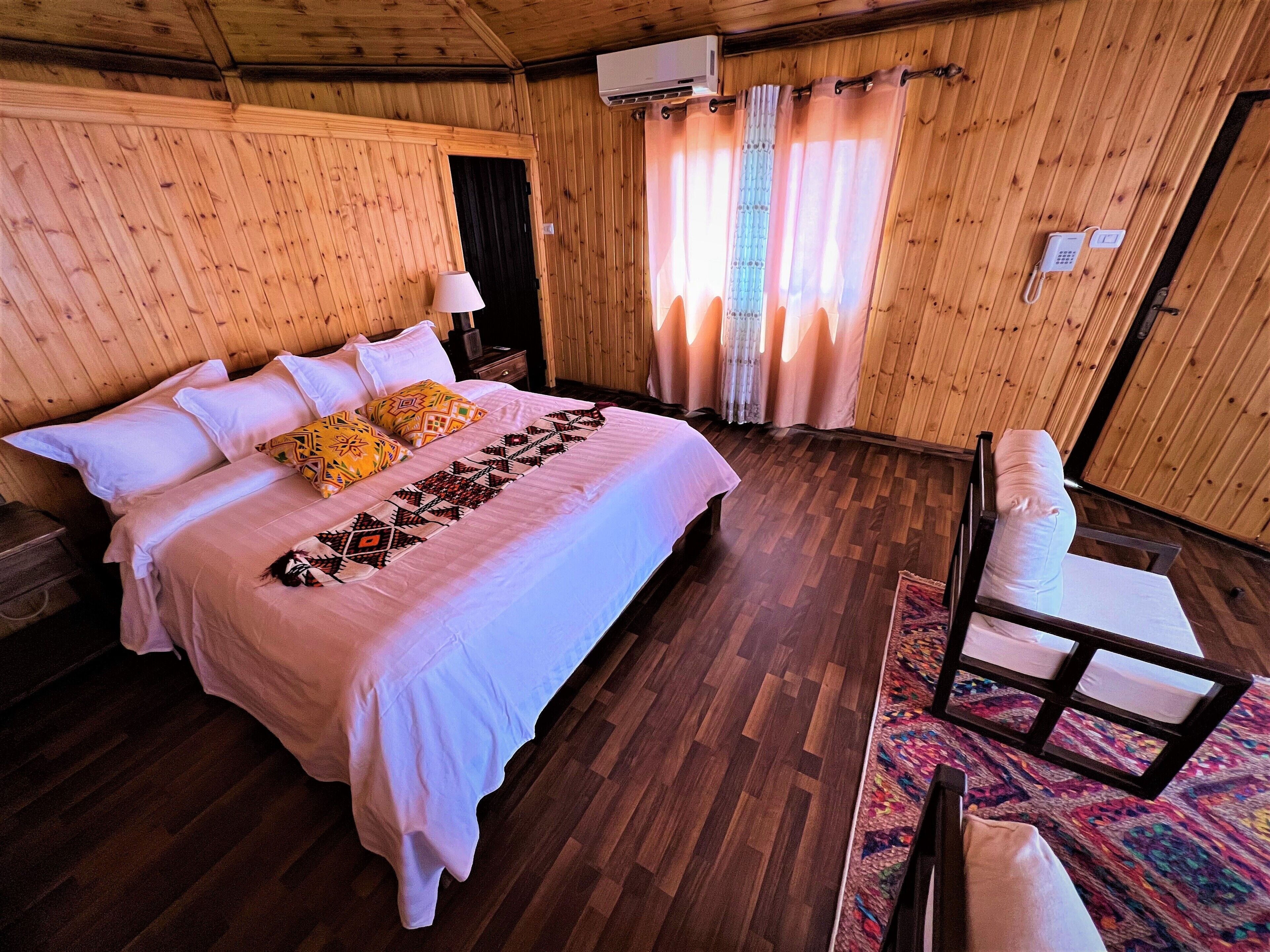 A wooden-paneled room with a bed, a chair, and a small table.