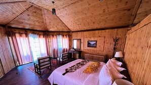 Una camera da letto in una casetta di legno, con un letto, due poltrone, una scrivania e una culla.