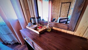 Un bancone in legno con un vassoio che contiene una tazza, bicchieri e una bottiglia. Uno specchio riflette l'ambiente circostante, e si vede una finestra con tende.