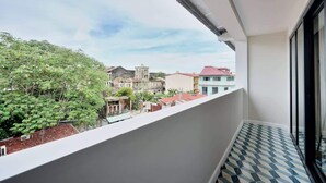 Un balcon donnant sur des immeubles et des arbres.