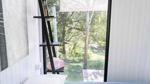 Une chambre à coucher avec un lit, une fenêtre et une vue sur un jardin.