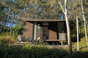 Een moderne, gelijkvloerse hut met een plat dak, omgeven door bomen.
