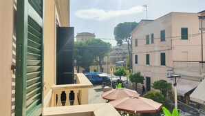 A narrow street with buildings on either side, a blue bus in the distance, and outdoor seating with umbrellas. - Bordopineta Center - Central and bright apartment (Pineto)