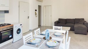 A modern kitchen with a gas stove, washing machine, and a dining area with a table set for two. - Bordopineta Center - Central and bright apartment (Pineto)