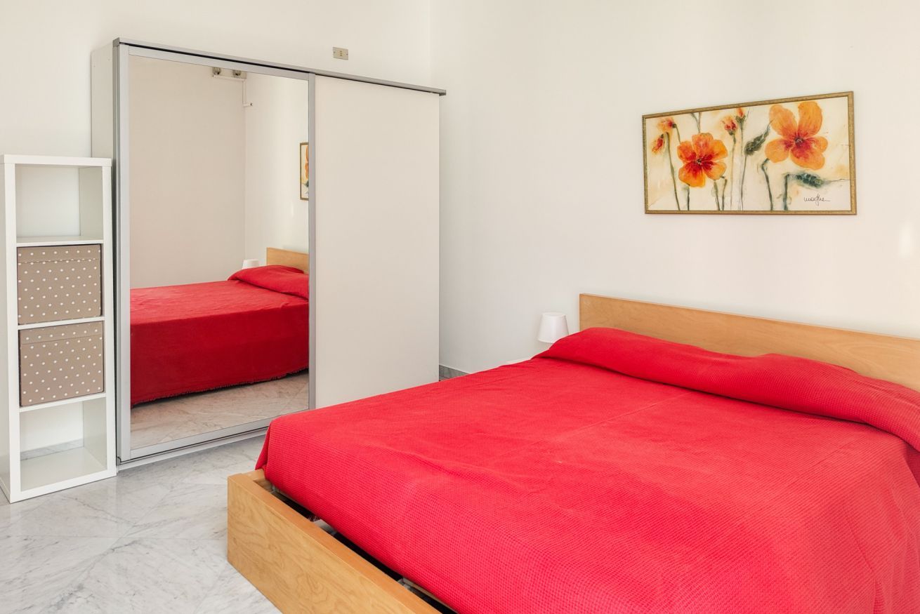 Een slaapkamer met een bed, een kledingkast en een schilderij aan de muur.