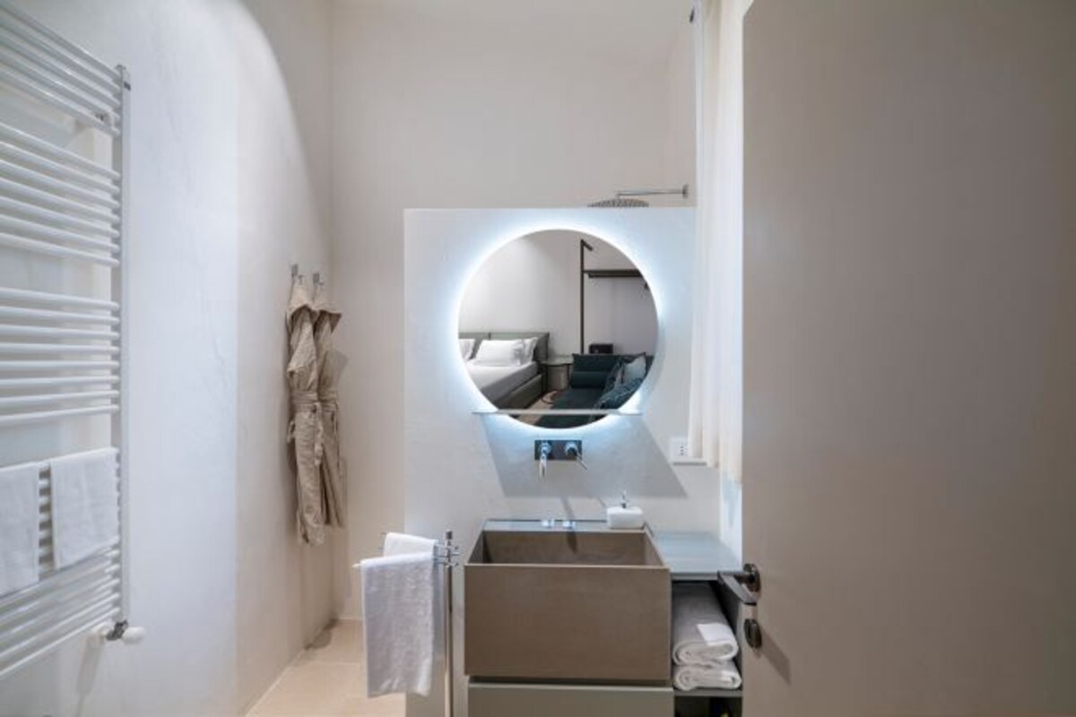 Un baño moderno con lavamanos integrado, un espejo redondo y un perchero para toallas.