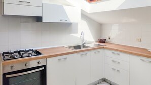 Eine moderne Küche mit weißen Schränken, einer Holz Arbeitsplatte, einem Gasherd und einem Oberlicht über der Spüle.
