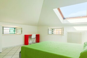 A room with a skylight, a bed with a green bedspread, a desk with a red cabinet, and a radiator. - Homiday - Bordopineta Center - Bright and spacious apartment on the second floor (Pineto)