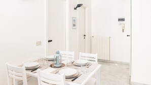 Un comedor con una mesa blanca dispuesta para cuatro, sillas blancas y un farol azul claro.