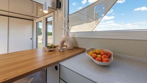 Et køkken med en træbordplade, en skål med frugt og en vase med grene.