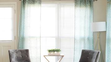 A room with two armchairs, a small table with a plant, and a floor lamp.