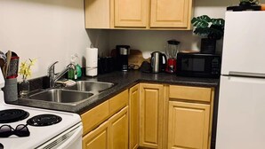 A kitchen with wooden cabinets, a stove, a sink, a microwave, and a refrigerator. - Pet-Friendly, Lovely Studio w/ Balcony (Halifax)