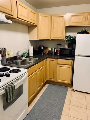 A kitchen with wooden cabinets, a stove, a sink, a microwave, and a refrigerator.