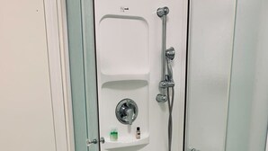 A bathroom with a toilet, a glass-enclosed shower, and a white sink with a soap dispenser. - Pet-Friendly, Lovely Studio w/ Balcony (Halifax)