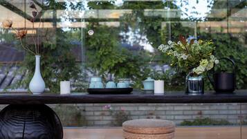 A table with a vase, candles, a metal watering can, and a tray with teapots.