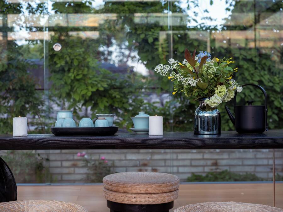 A table with a vase, candles, a metal watering can, and a tray with teapots.