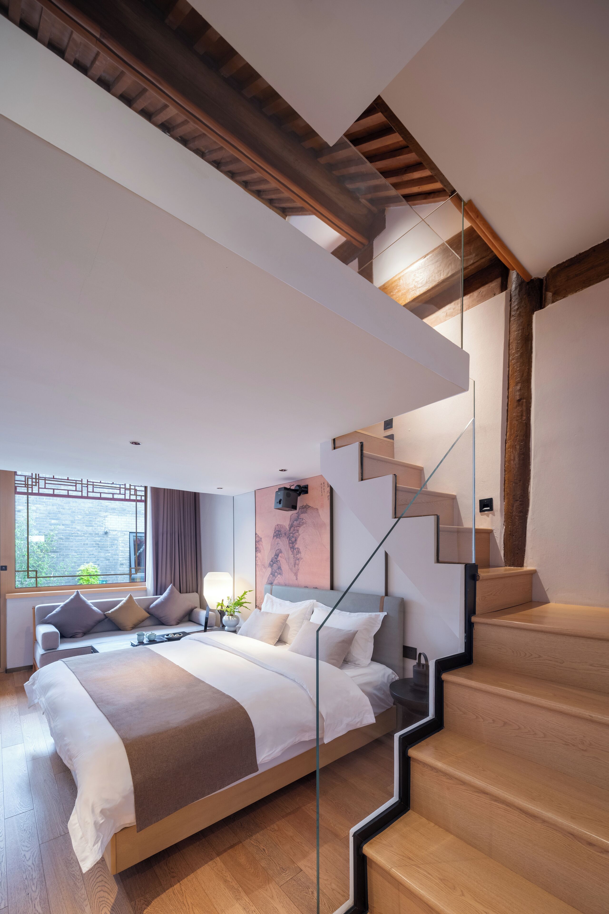 A modern bedroom with a large bed, a glass staircase, and a view of the outdoors.