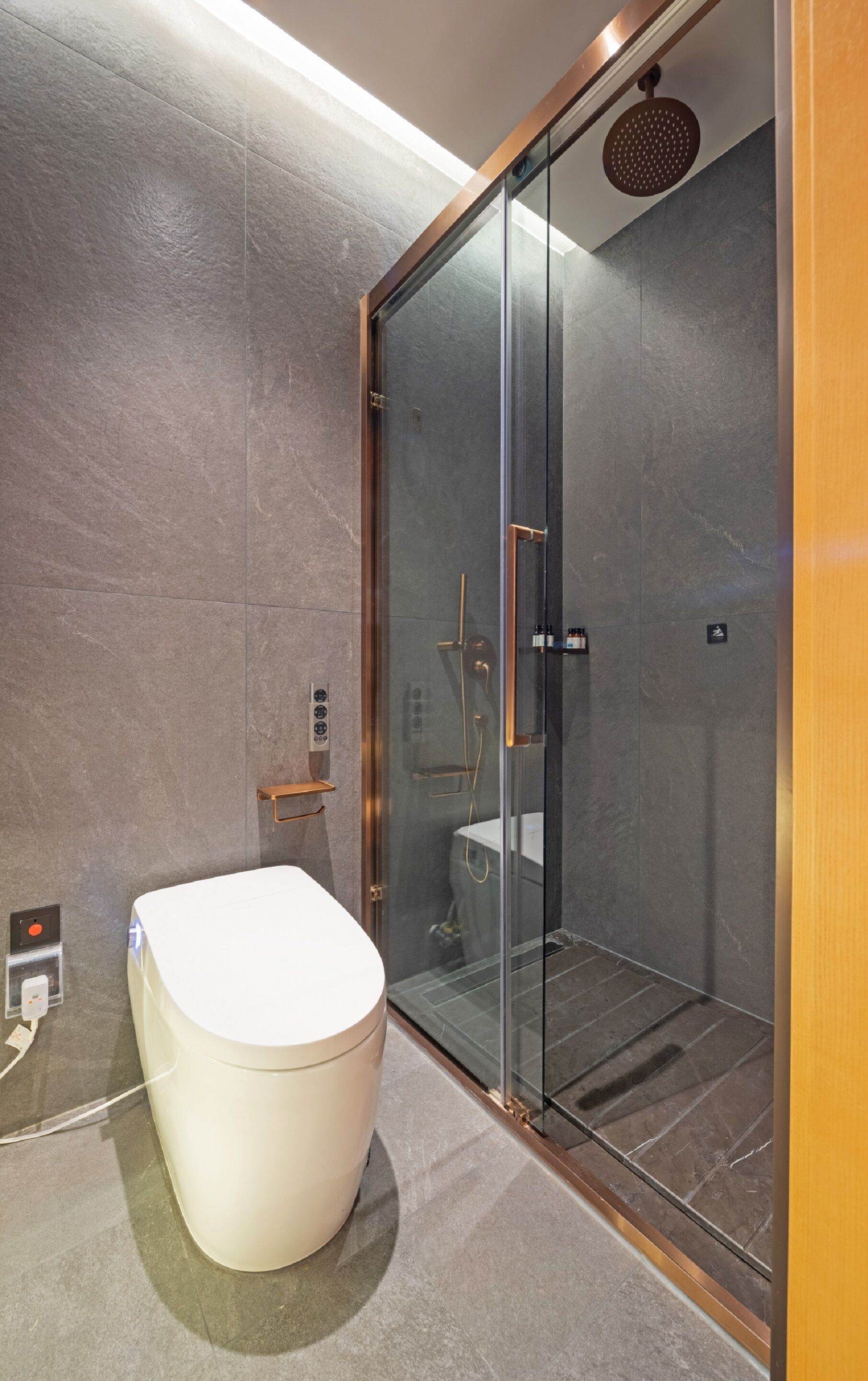 A modern bathroom with a glass-enclosed shower, a white toilet, and a built-in sink.