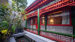 A traditional building with red and green accents, a brick facade, and a small water feature with fish. - XinXiangYaYuan Courtyard (Beijing)