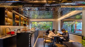 A restaurant with a modern interior, a bar area, and a view of greenery outside. - XinXiangYaYuan Courtyard (Beijing)
