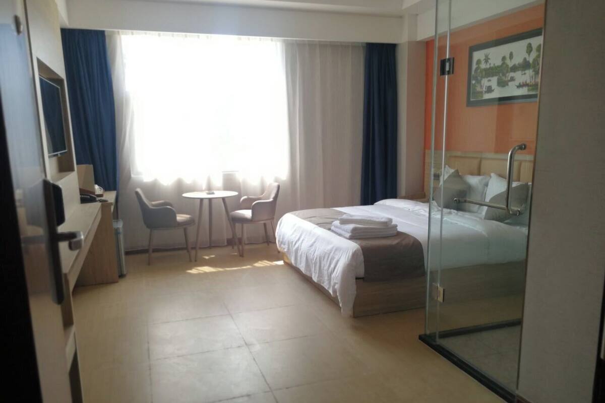 A hotel room with a bed, a desk, a chair, and a small table.