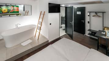 A modern bathroom with a freestanding bathtub, a wooden ladder, and a mirror with a floral painting.