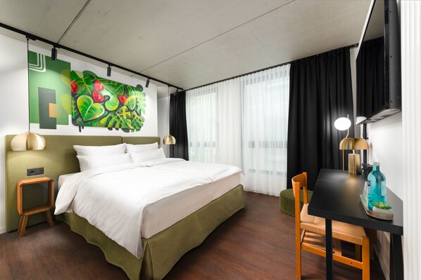 A hotel room with a bed, a desk, a chair, a lamp, and a painting on the wall. - The Barthels Boutique Hotel (Würzburg)
