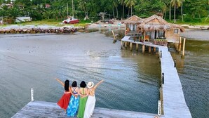 A wooden pier extending into a body of water with a backdrop of lush greenery and a mountain. - Freedom Beach Resort (Phu Quoc)