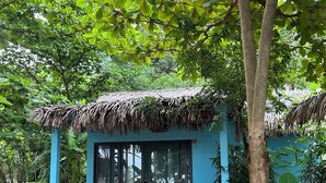 A small blue building with a thatched roof, surrounded by lush greenery. - Freedom Beach Resort (Phu Quoc)