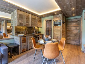 A rustic kitchen with wooden cabinets, a dining table with chairs, and a built-in oven. - Superb Ski-In/Ski-Out Apartment with Covered Parking and WiFi in Val-d'Isère (Val-d'Isère)