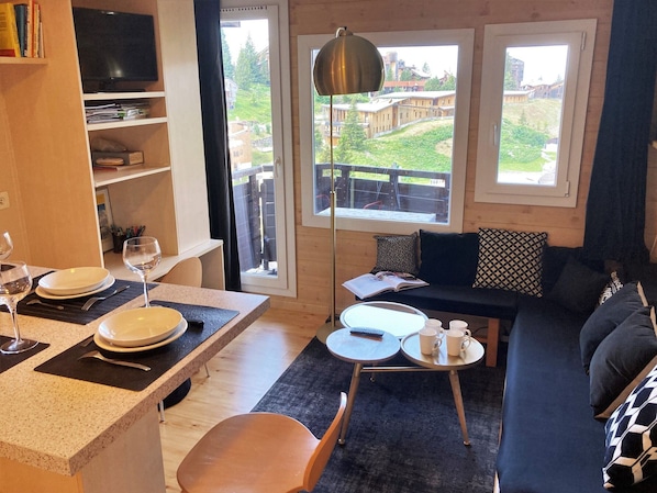 A cozy living room with a dining area, a sofa, and a TV.