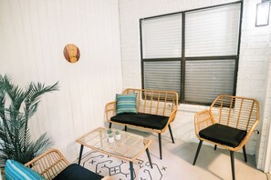 Relax in this serene outdoor seating area with a wicker chair, small table, and potted plant.