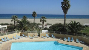 A pool area with lounge chairs and a view of the beach.